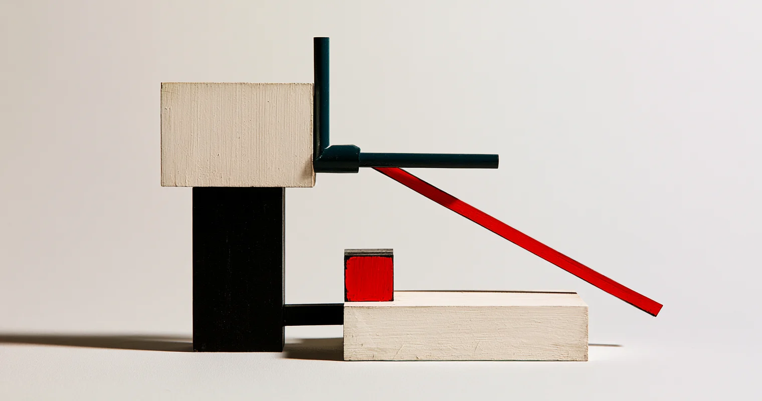 Frontvänd trämaquette med staplade benvita och svarta block, en mörkt turkos vinkelarm och en lång röd diagonal framför en låg benvit plattform med en liten röd kub.